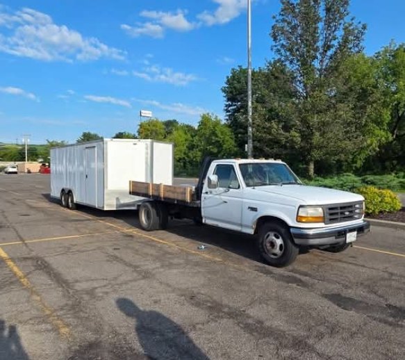 Flatbed truck towing an enclosed cargo trailer
